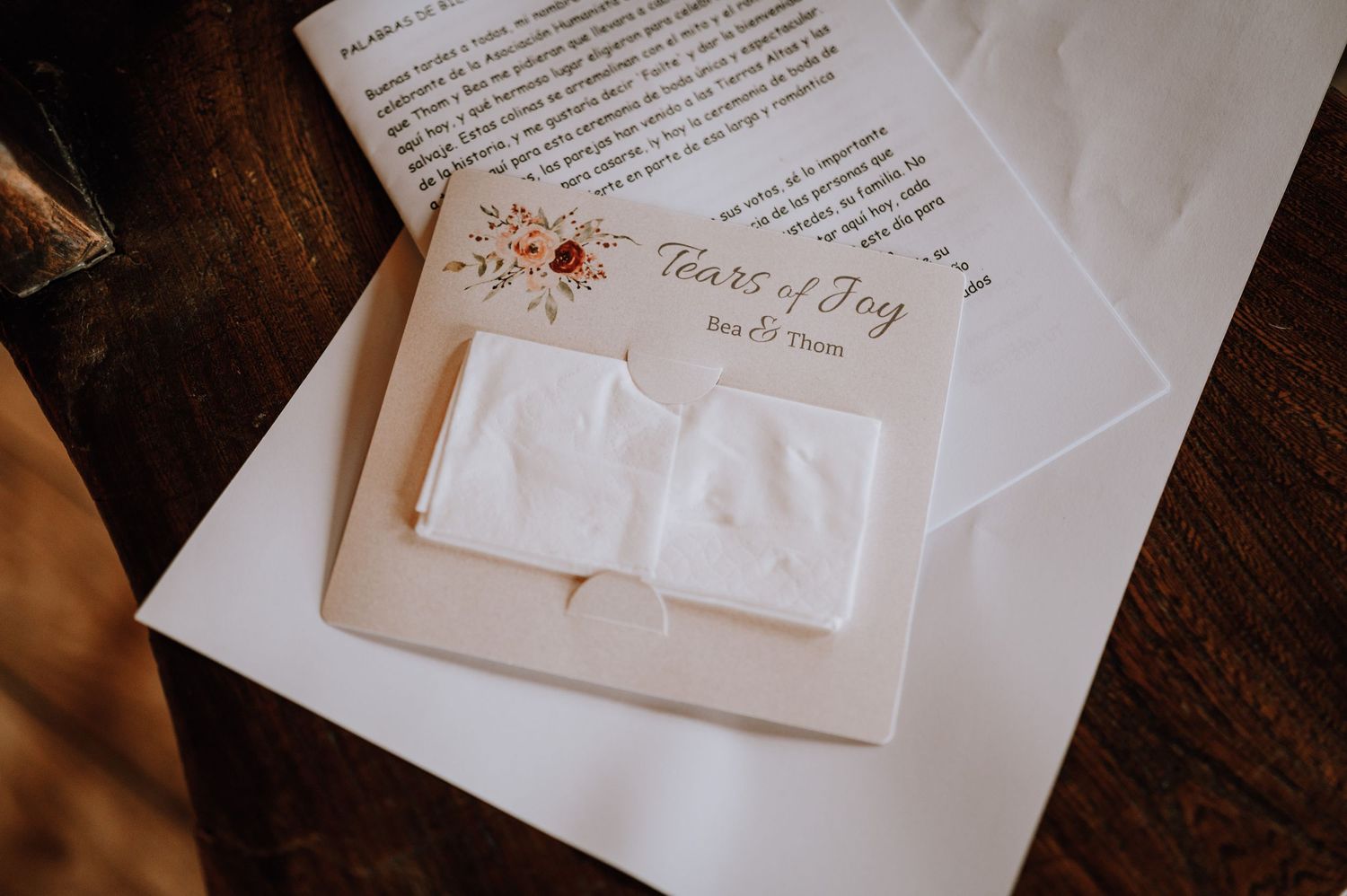 Wedding stationery and invitation details captured in warm lighting on a wooden surface.