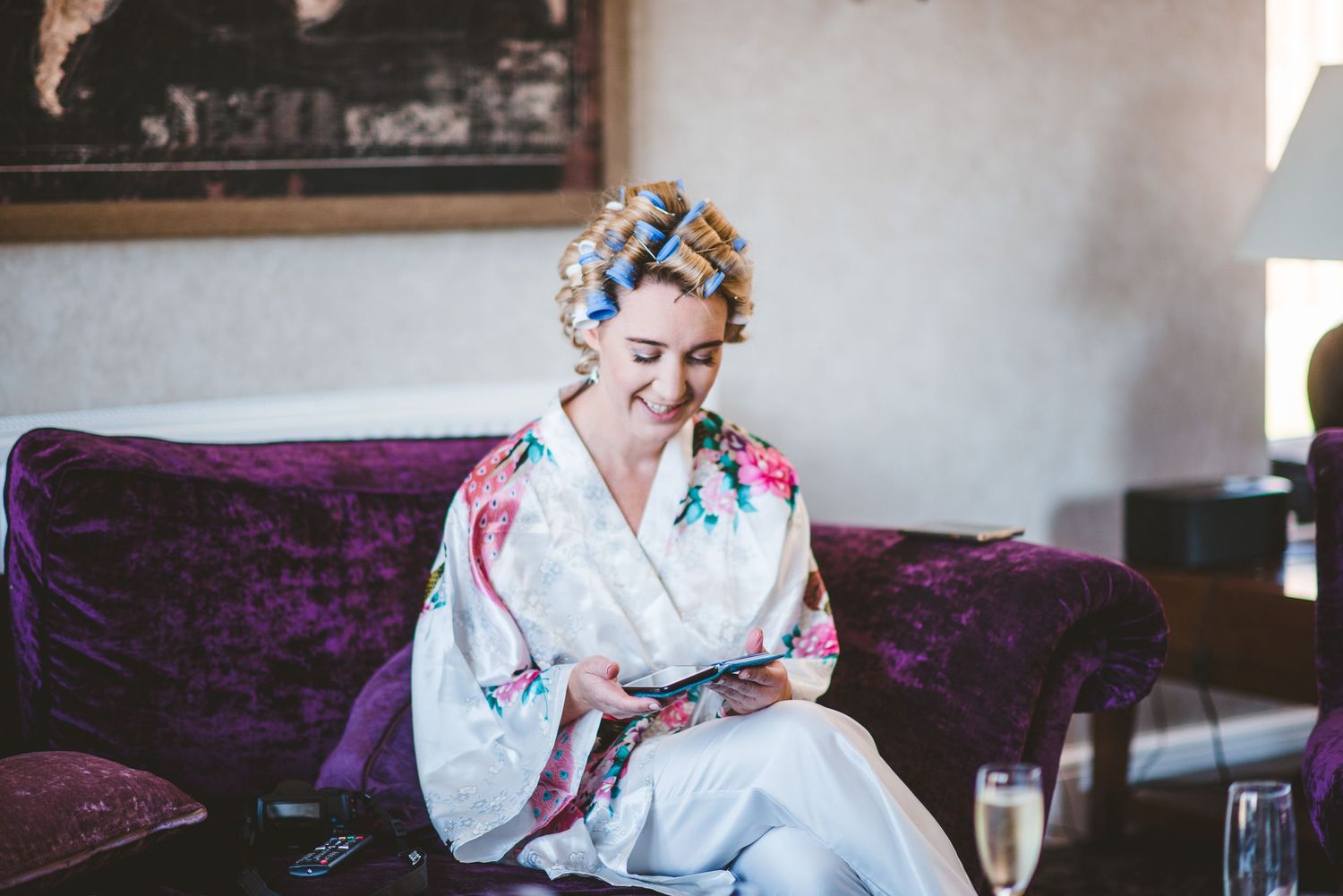 Wedding preparations with hair styling and makeup in a bright room.