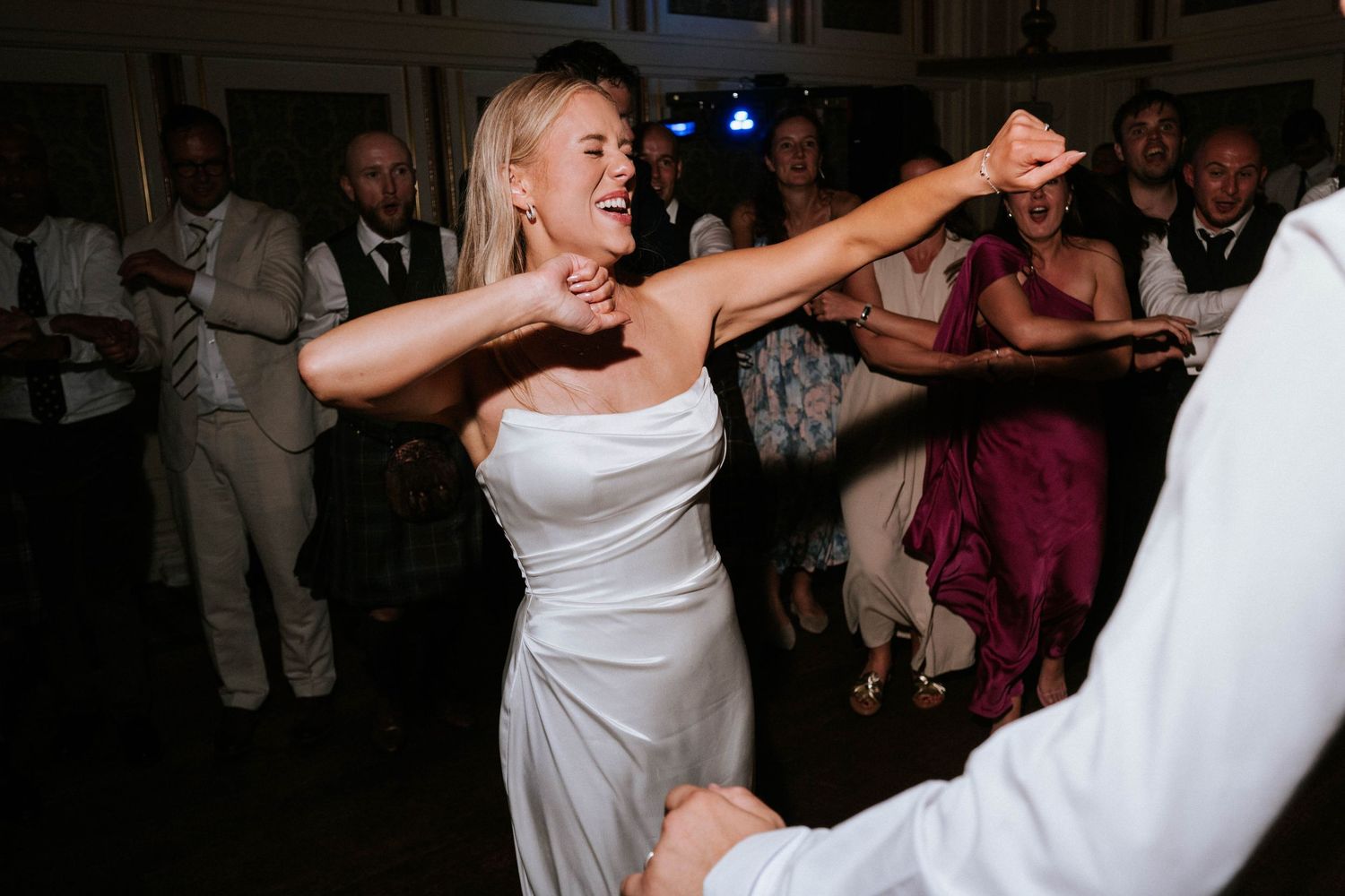 Lively wedding reception dance party with guests enjoying themselves on the dance floor.