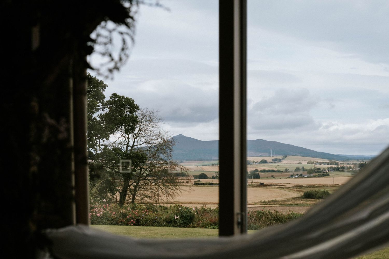 Panoramic mountain landscape view through a window showing rolling hills and cloudy skies.