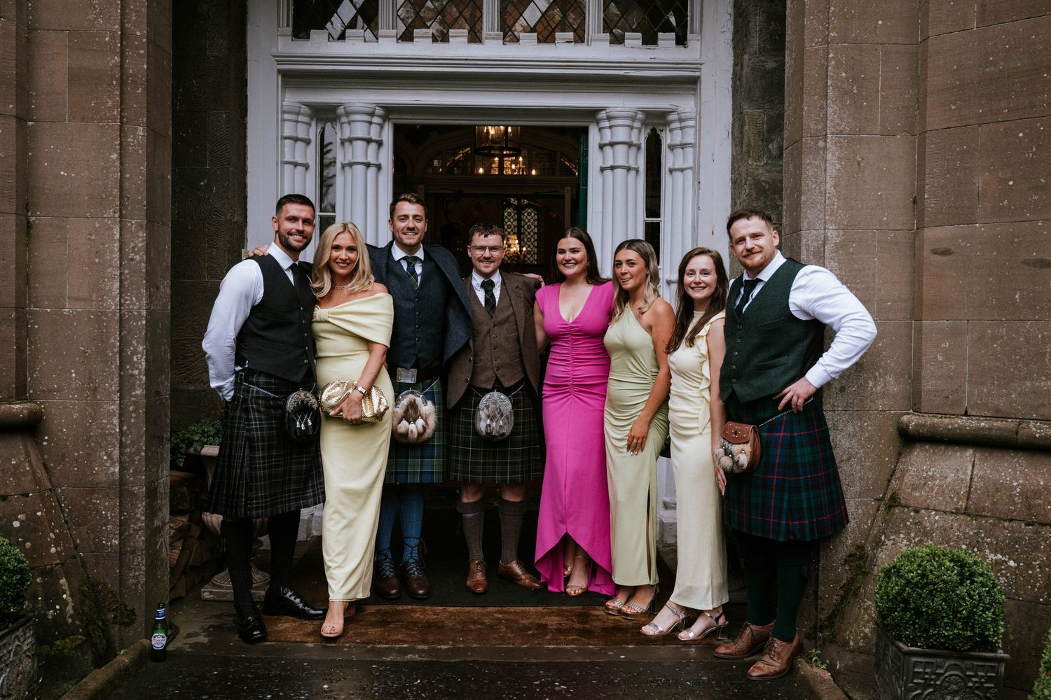 Wedding party poses for photos in front of a grand stone church entrance with gothic architecture.