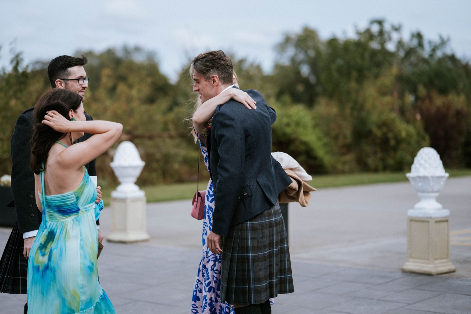 Wedding guests in formal attire sharing an emotional moment outdoors.