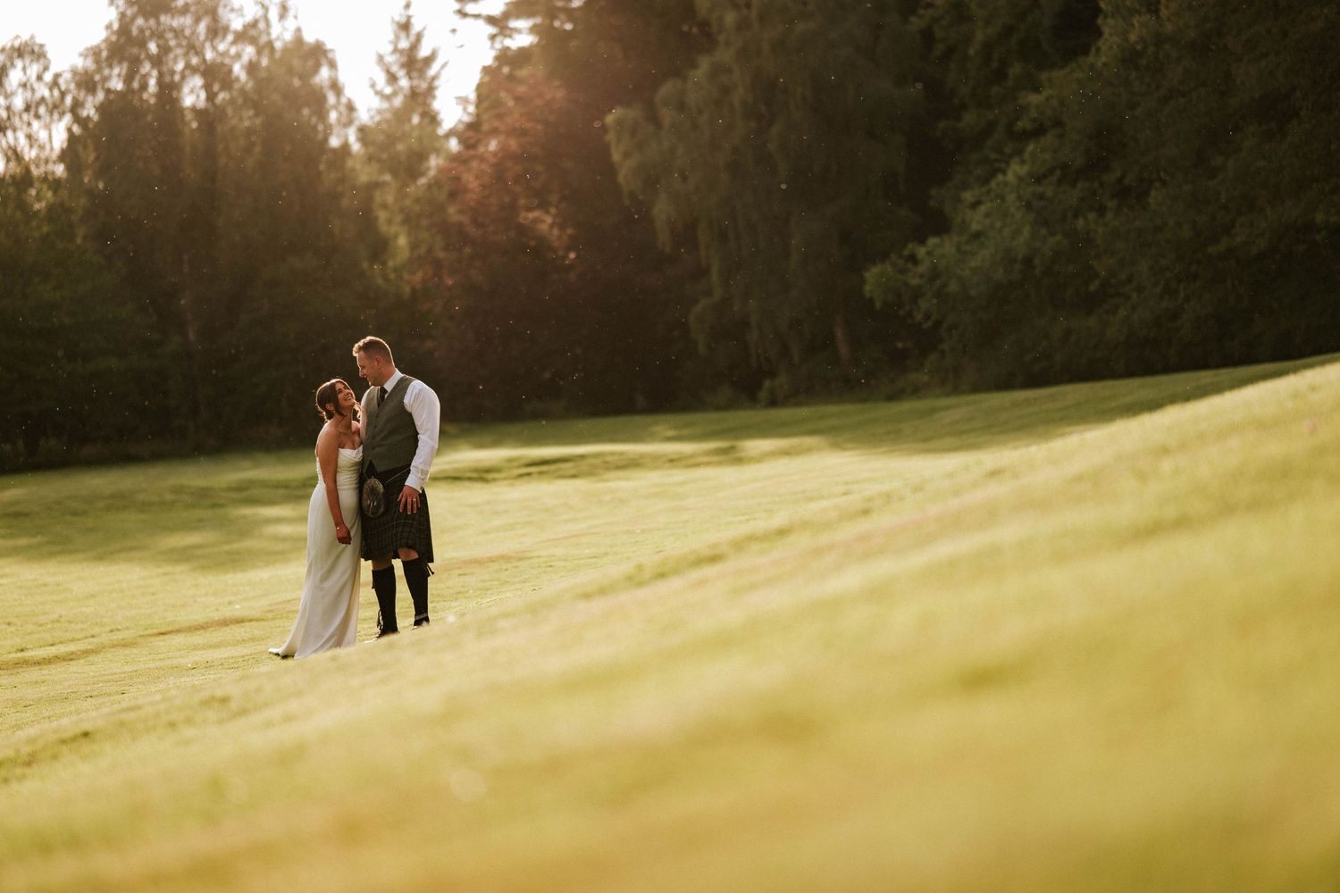 Aberdeen Wedding Photography. Couple shares intimate moment at sunset on a rolling green hillside.