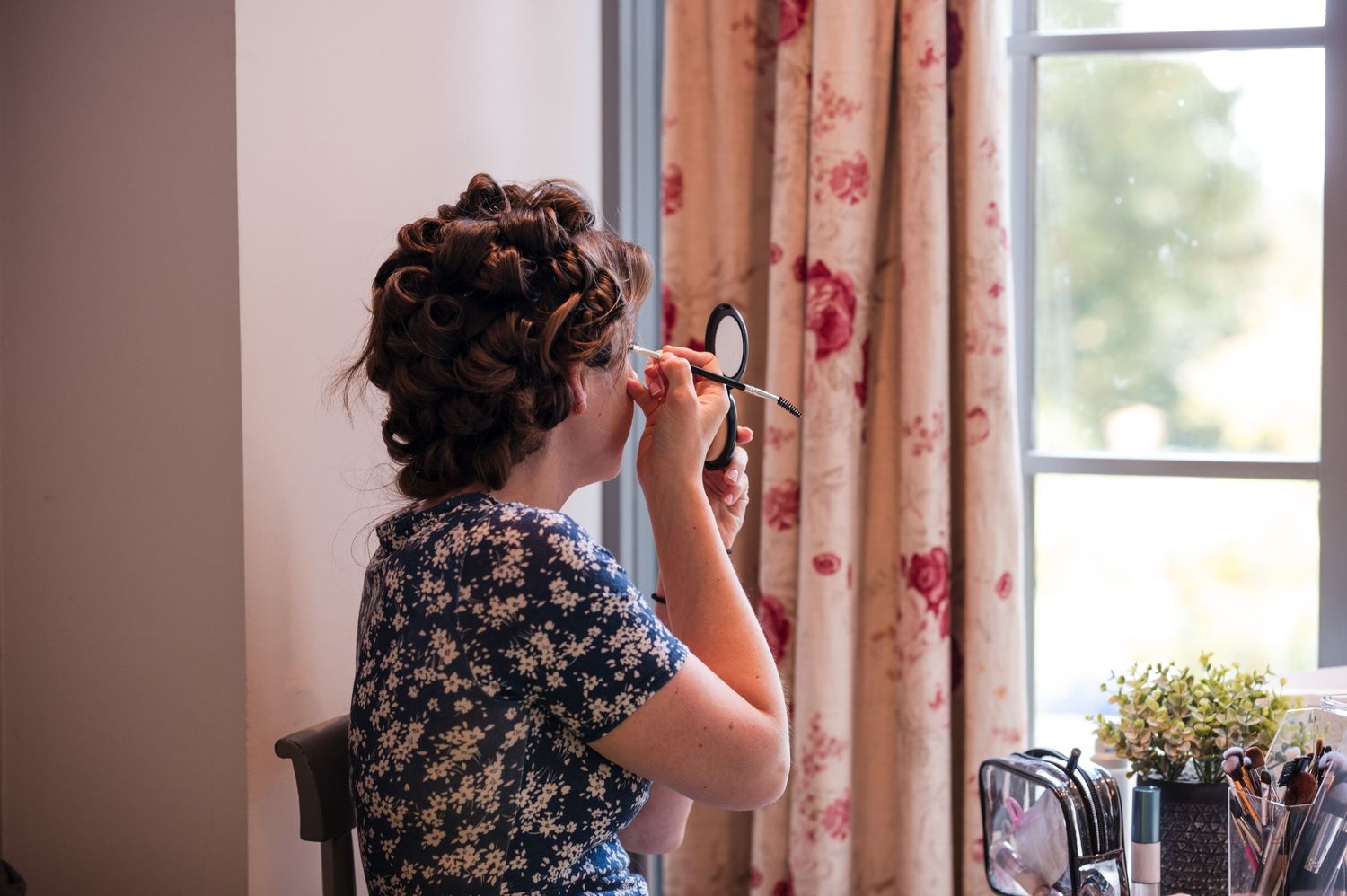 Candid moments captured through windows with floral curtains in a bright interior setting.