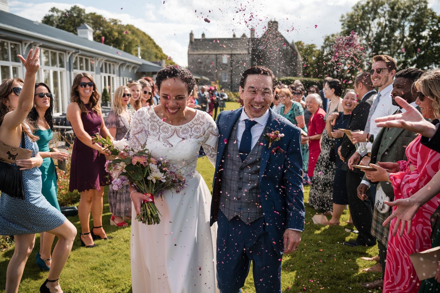 Wedding celebration with confetti being tossed in the air during an outdoor ceremony.