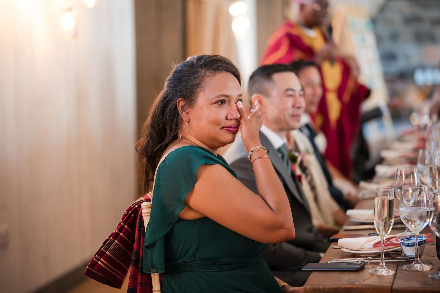 Wedding reception dinner guests seated at long tables indoors.