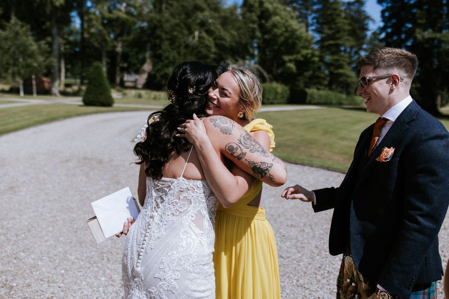 Fasque Castle Wedding Photography. Wedding party celebrates outdoors on a sunny day with confetti and joyful expressions.