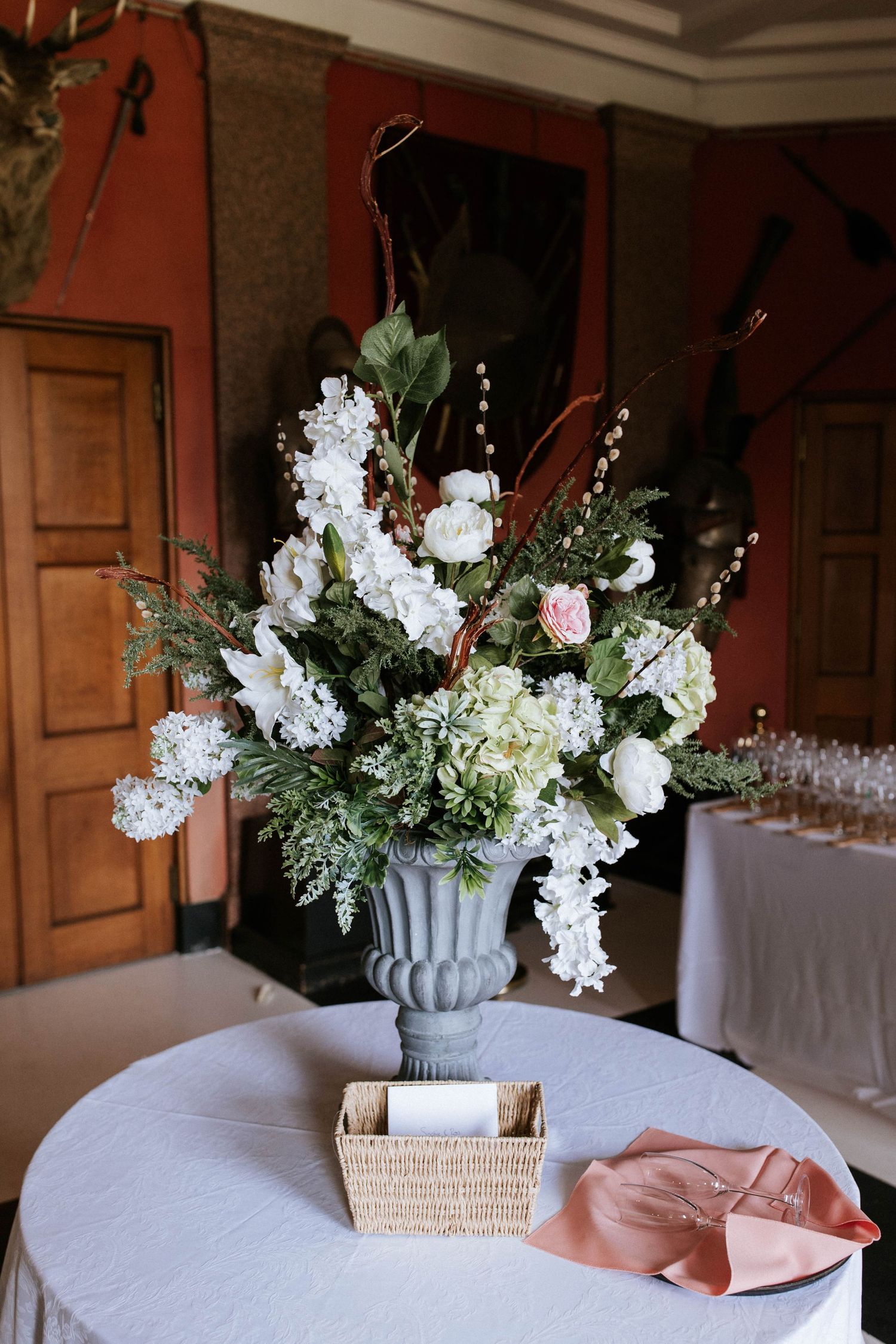 Elegant white and pink floral centerpieces in gray vases on tables with peach linens.