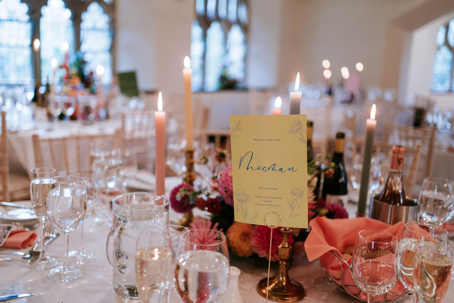 Wedding reception table setting with place cards and pink floral centerpieces.