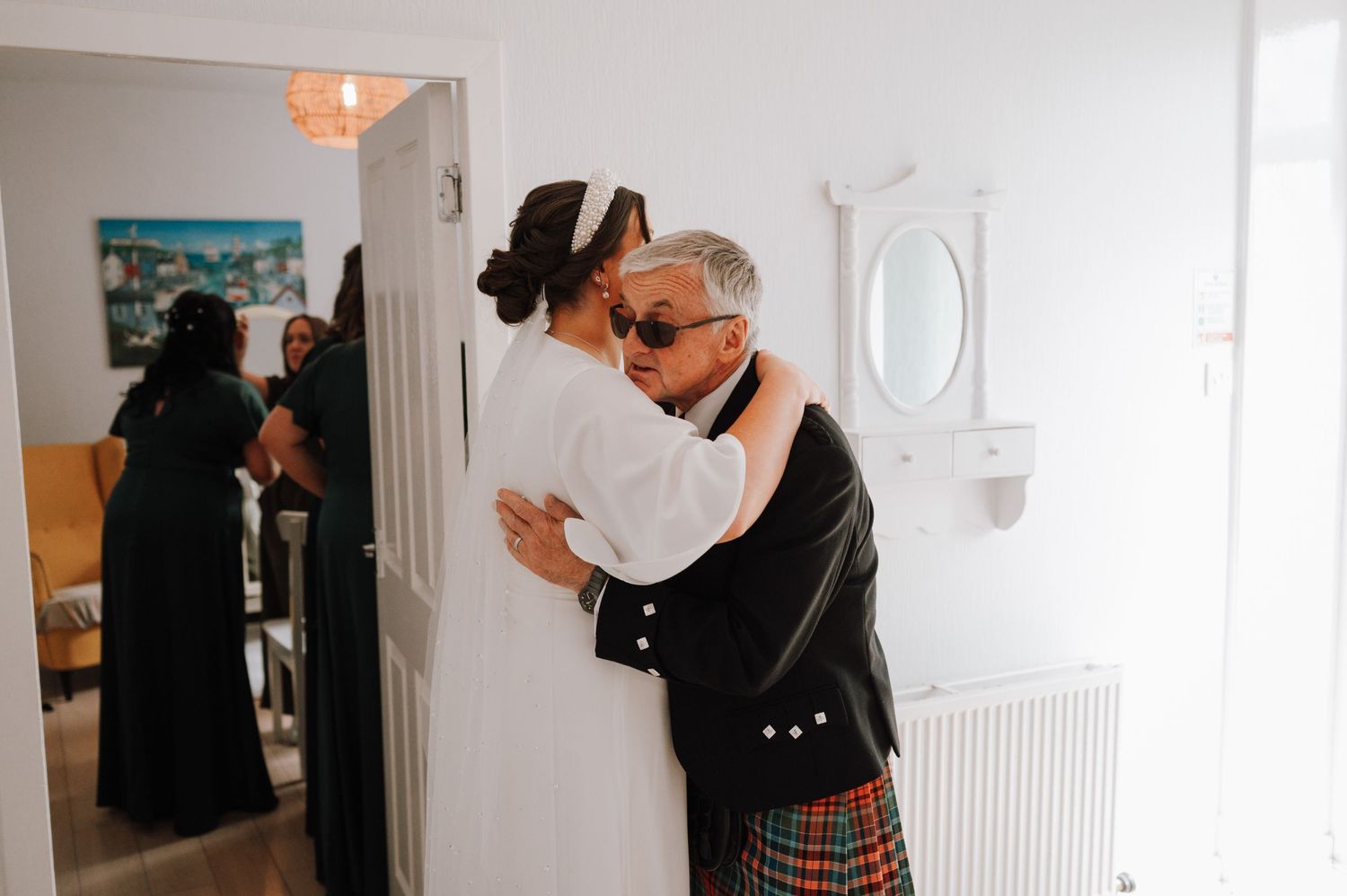 Someone embraces a wall, wearing a black cardigan and plaid skirt in an interior hallway.
