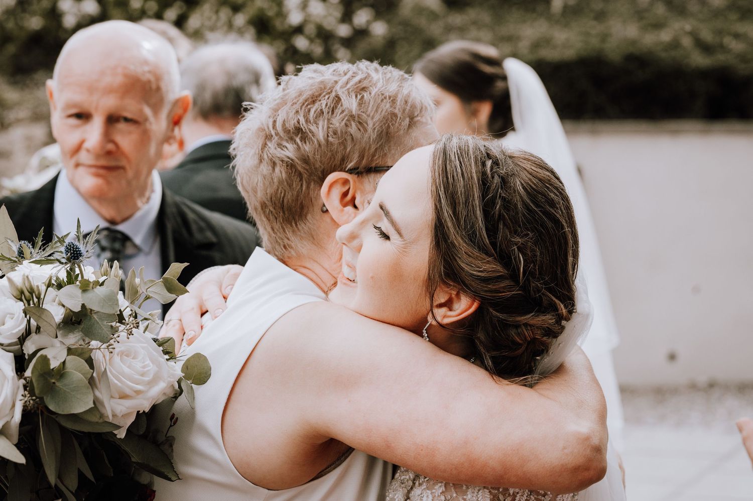 Tender embrace captured during emotional wedding celebration outdoors.