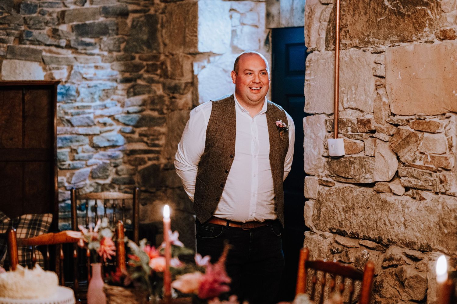 Intimate wedding ceremony setup in a rustic stone wine cellar with candle lighting.
