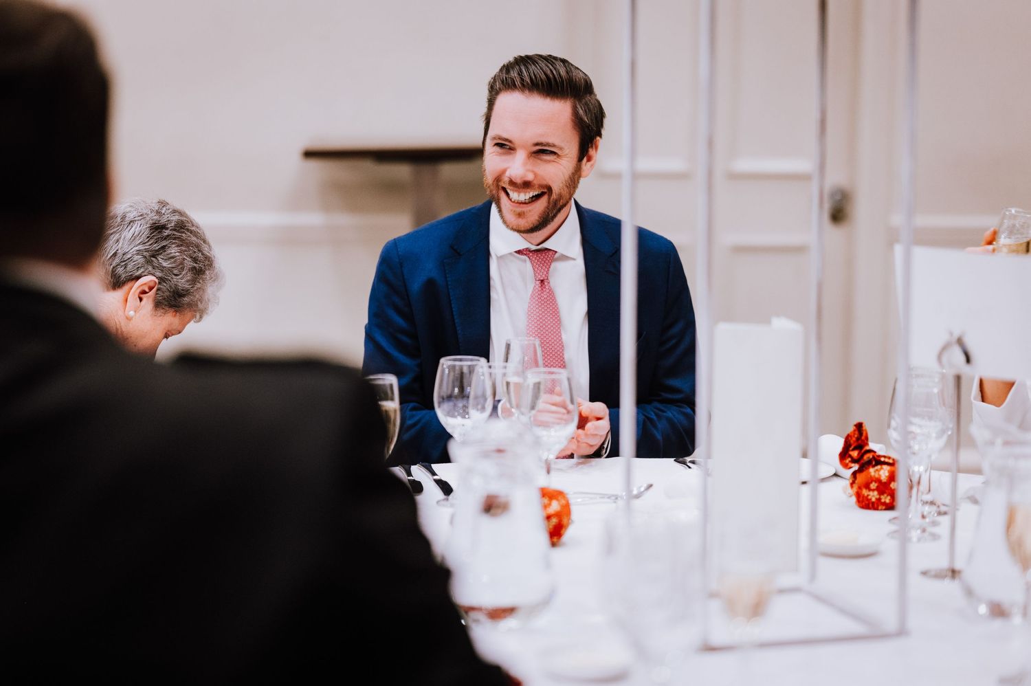 Guests enjoying conversation at an elegant wedding reception with white tablecloths and wine glasses.