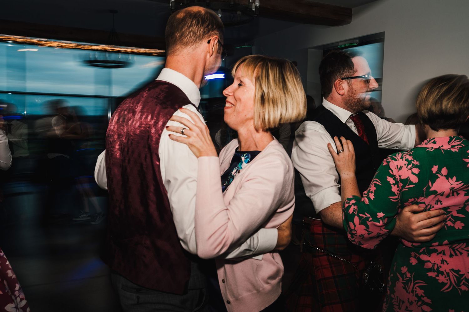 Couples slow dancing together at an evening celebration with mood lighting.