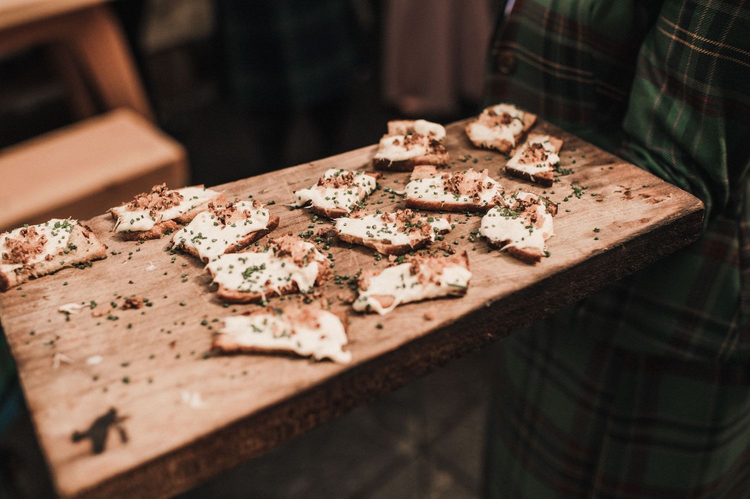 Chocolate bark or brittle desserts laid out on a wooden board with scattered crumbs and toppings.