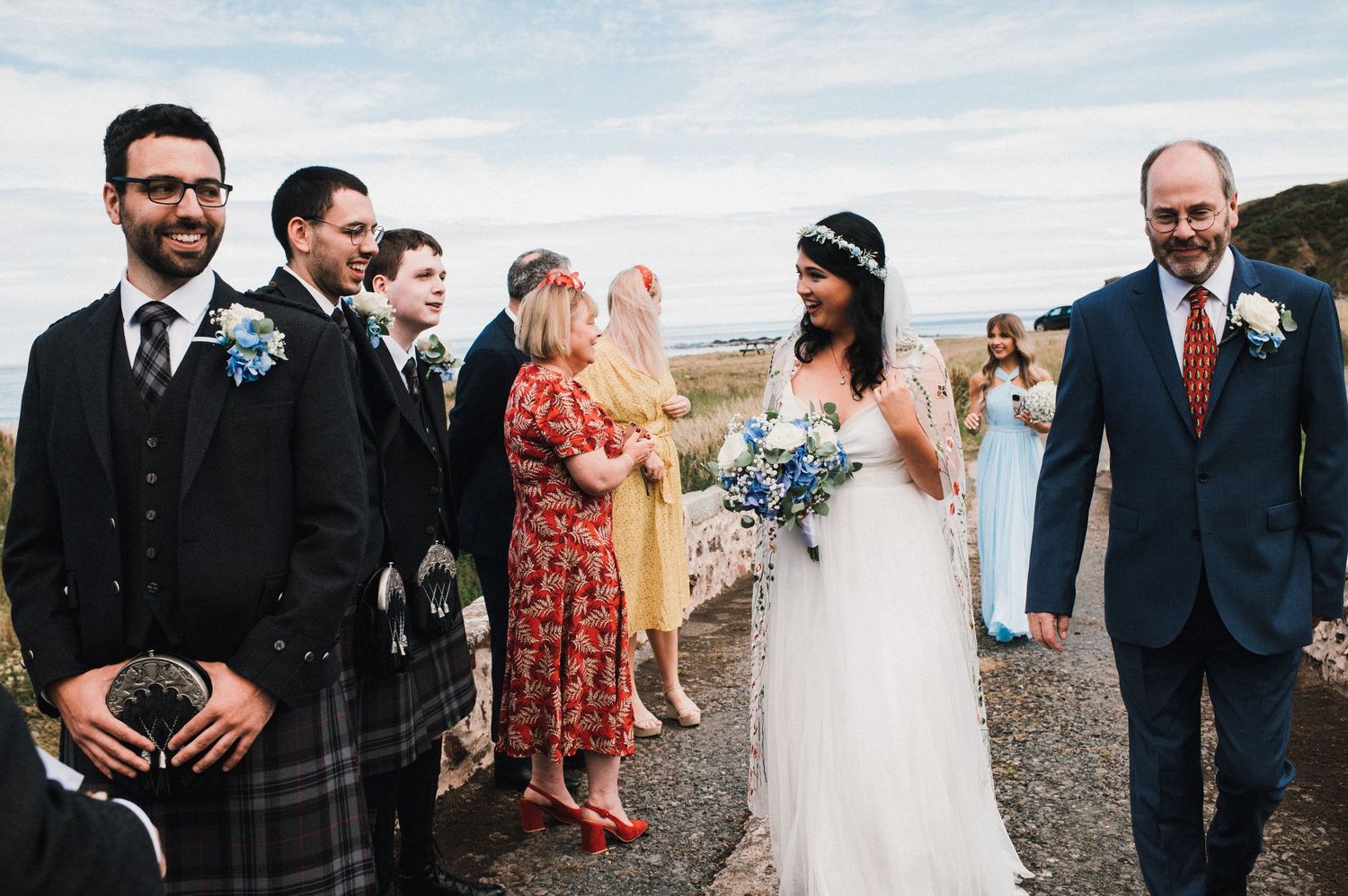 Wedding ceremony group gathered on coastal path with ocean views.