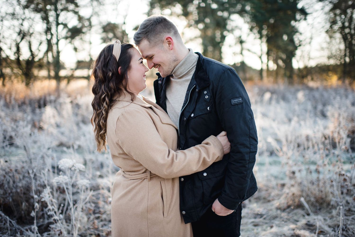 A romantic winter embrace captured against a backdrop of frost-covered foliage.