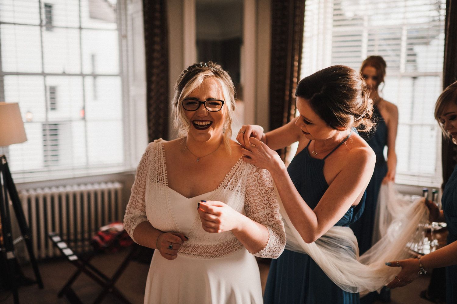Wedding preparation scene showing final adjustments being made in a bright room with classic decor.