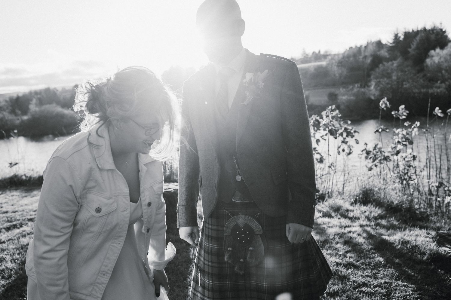 Black and white wedding photo with Scottish traditional dress in natural setting.