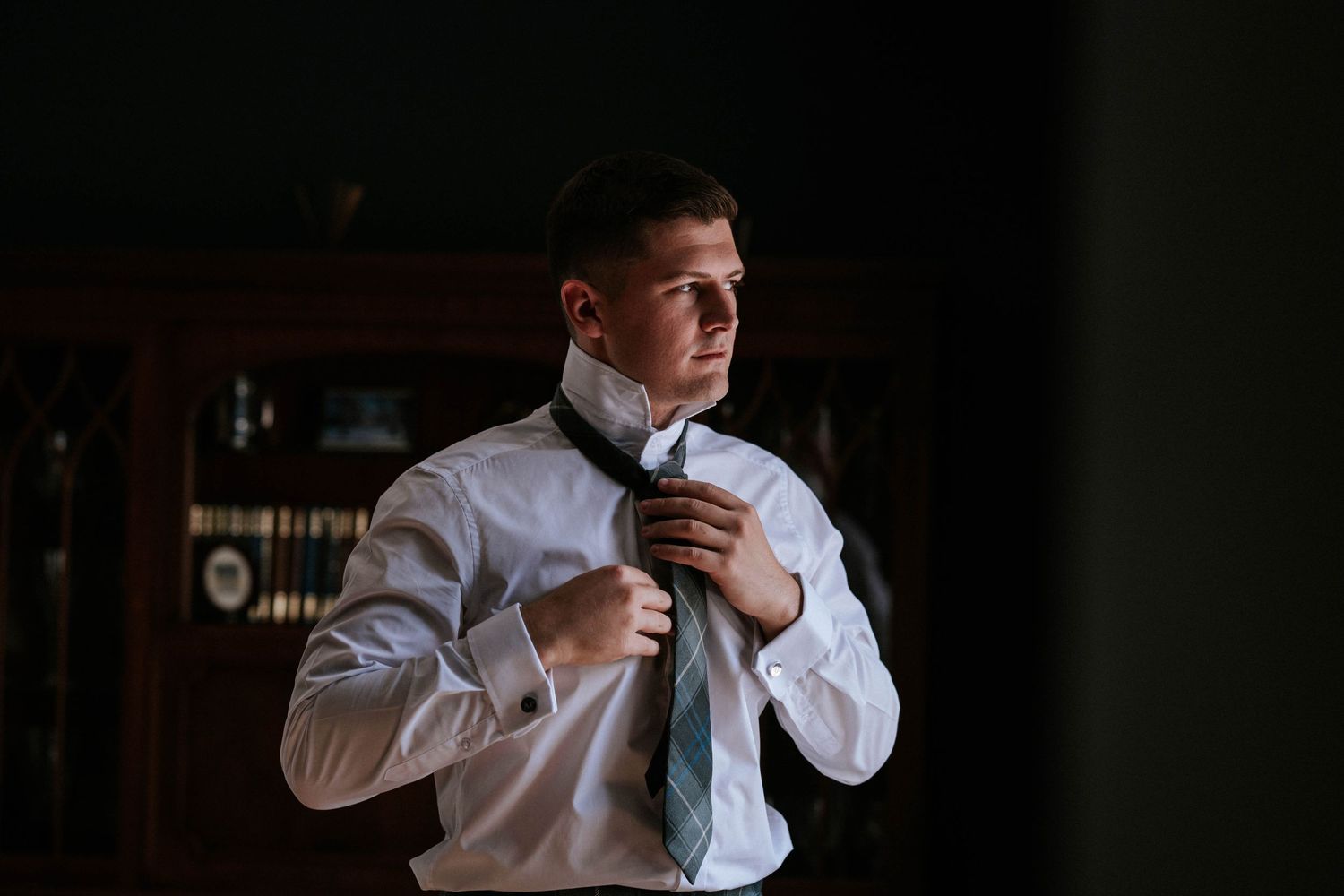 Aberdeen Wedding Photography. Groom adjusts his tie while getting ready in formal attire for wedding day.