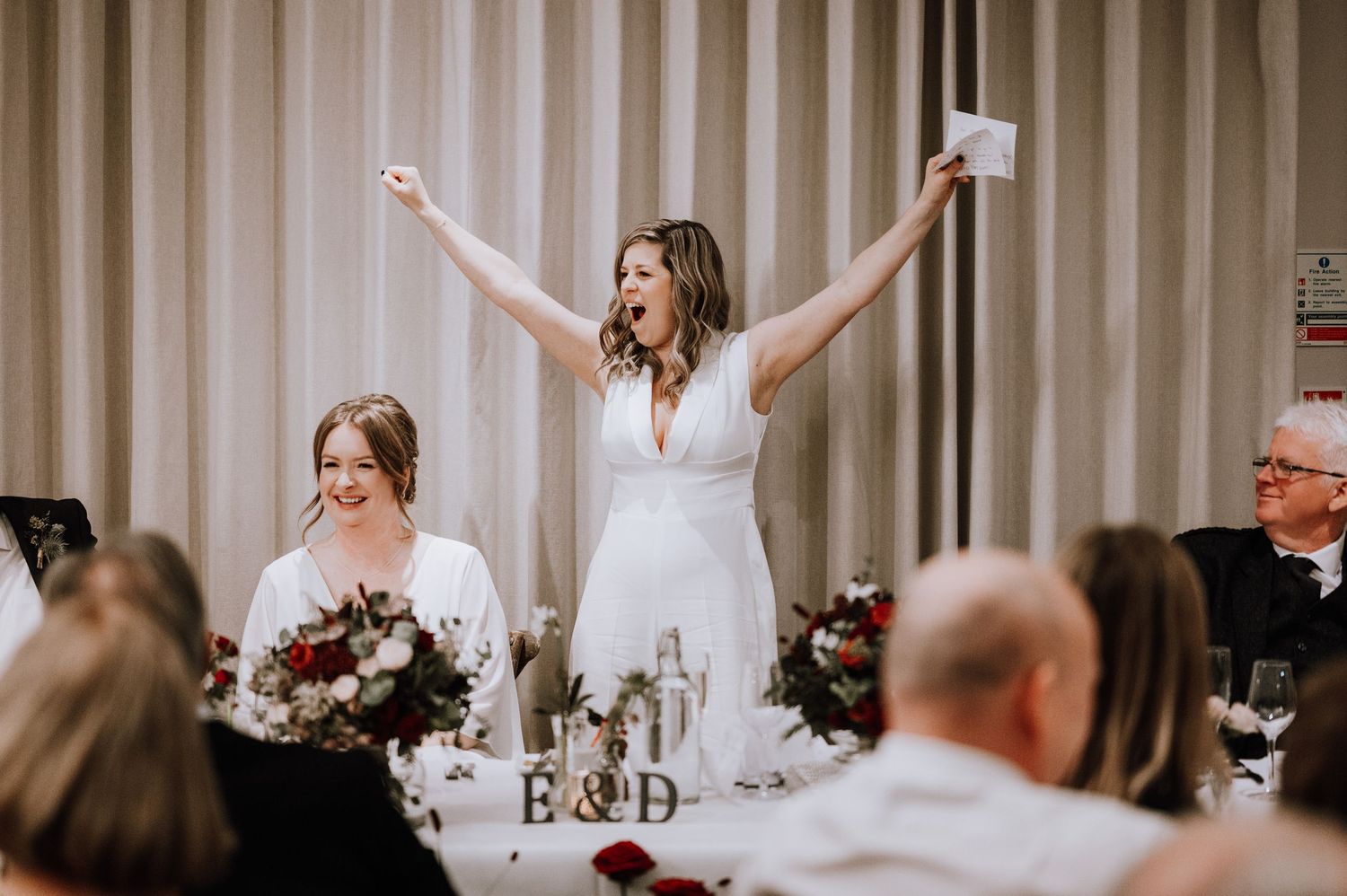 Same Sex Wedding Photography. Wedding reception guests celebrate at long tables decorated with floral centerpieces.