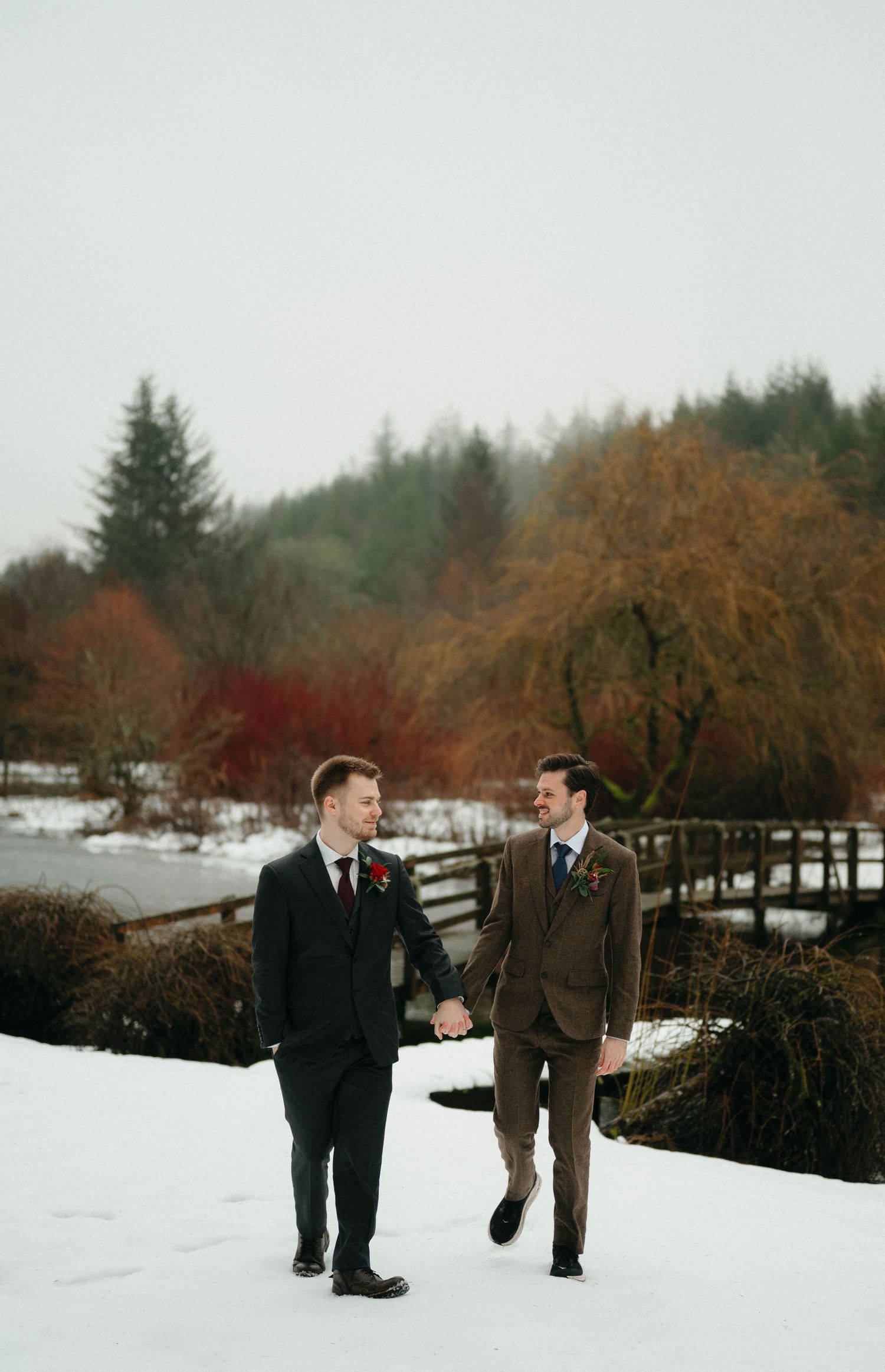 Drumtochty Castle  Wedding Photography. Two people walking through a snowy landscape with evergreen trees in the background.