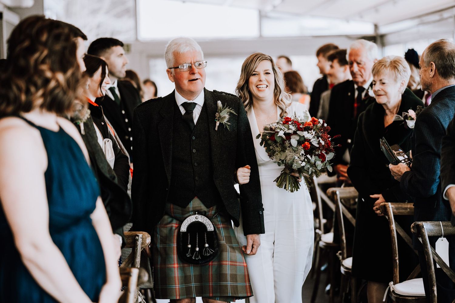 Same Sex Wedding Photography. Wedding guests gather under white tent during outdoor celebration.