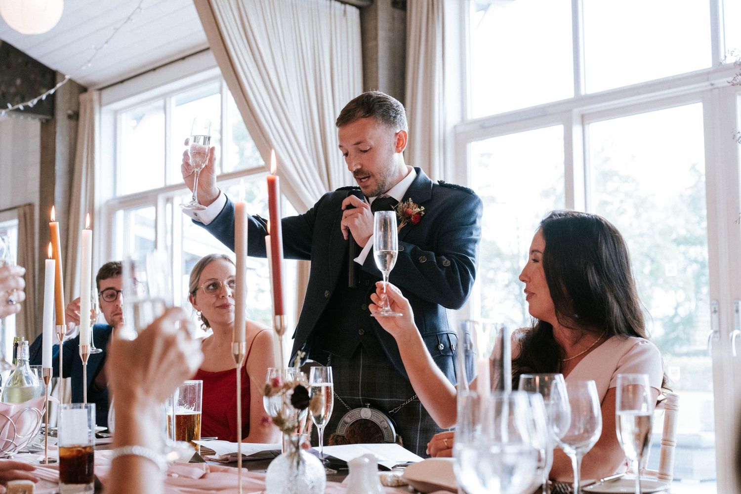 Wedding reception venue with bright windows and elegant white curtains during daytime celebrations.