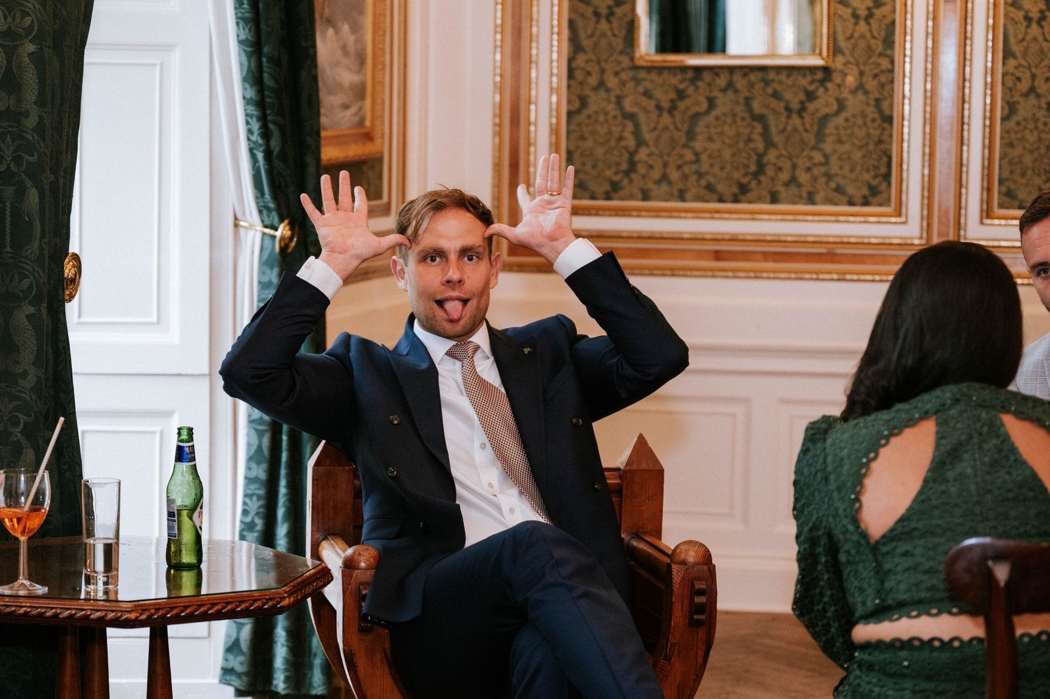 Guests enjoying drinks and conversation in a luxurious reception room with vintage furnishings.