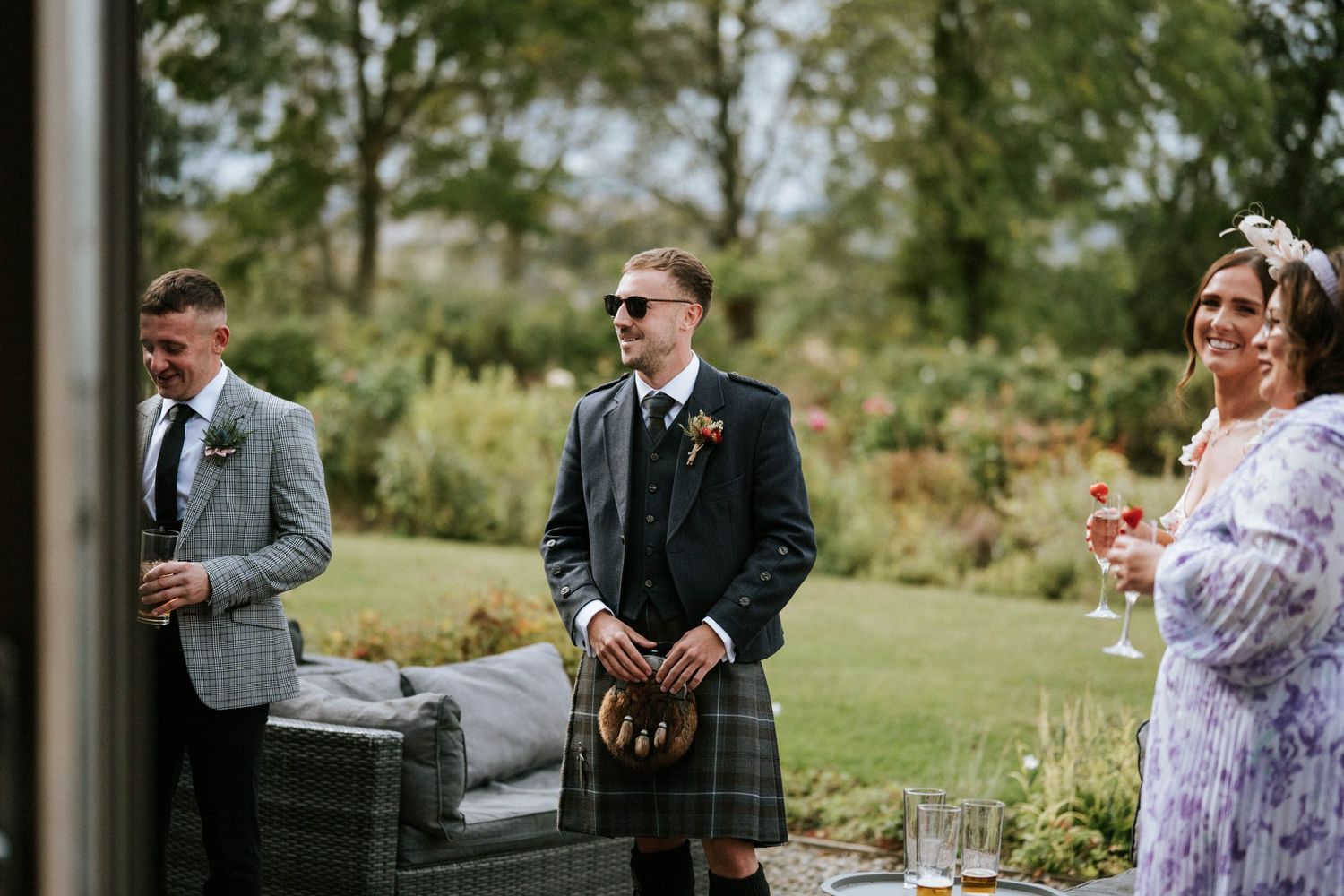 Wedding guests mingling on a sunny lawn during an outdoor reception.
