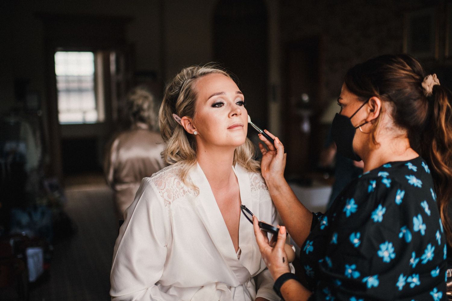 Professional makeup artist applies cosmetics during bridal preparation.