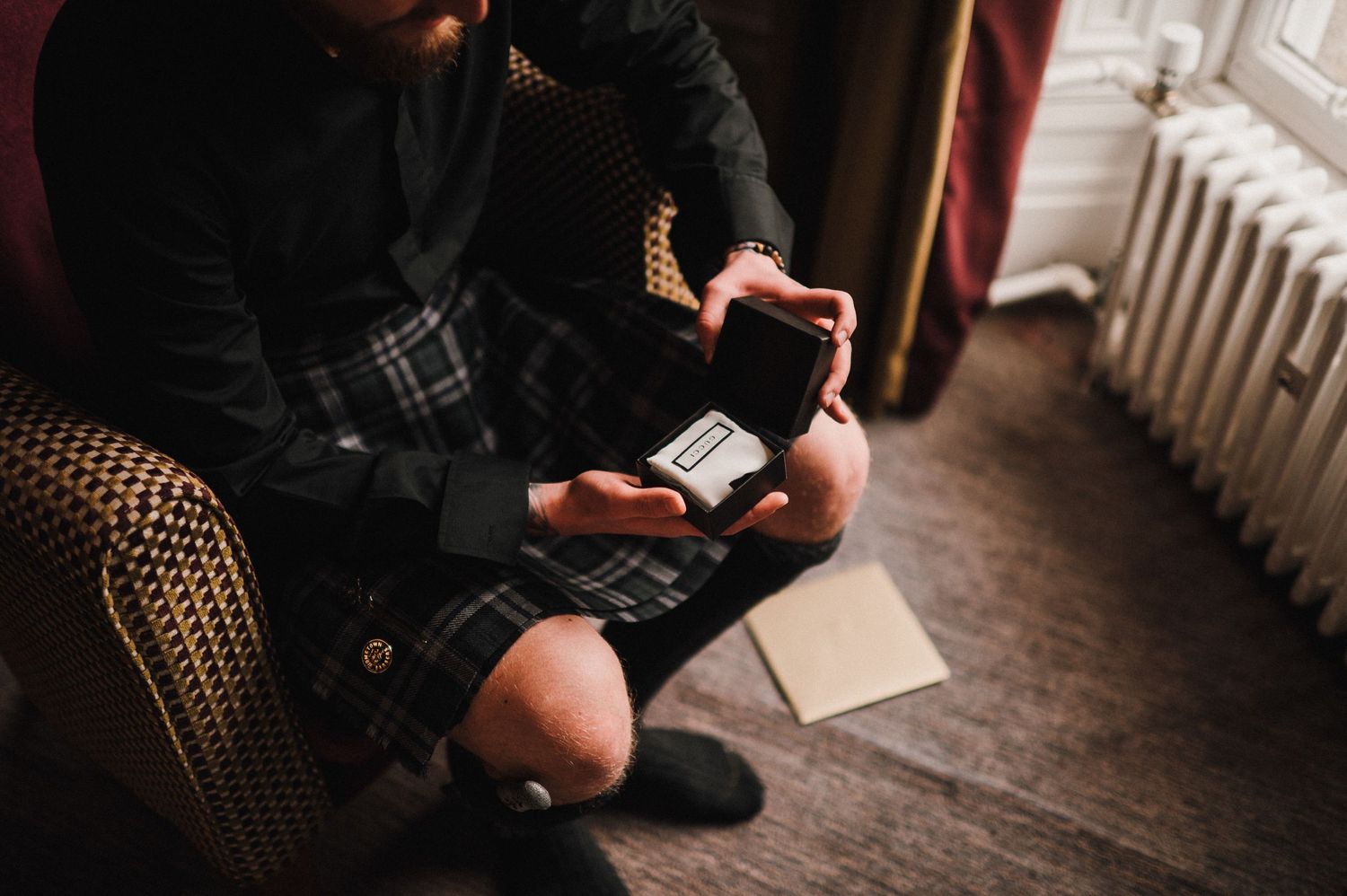 Close-up shot of hands holding and reading handwritten letters while seated in a patterned armchair.