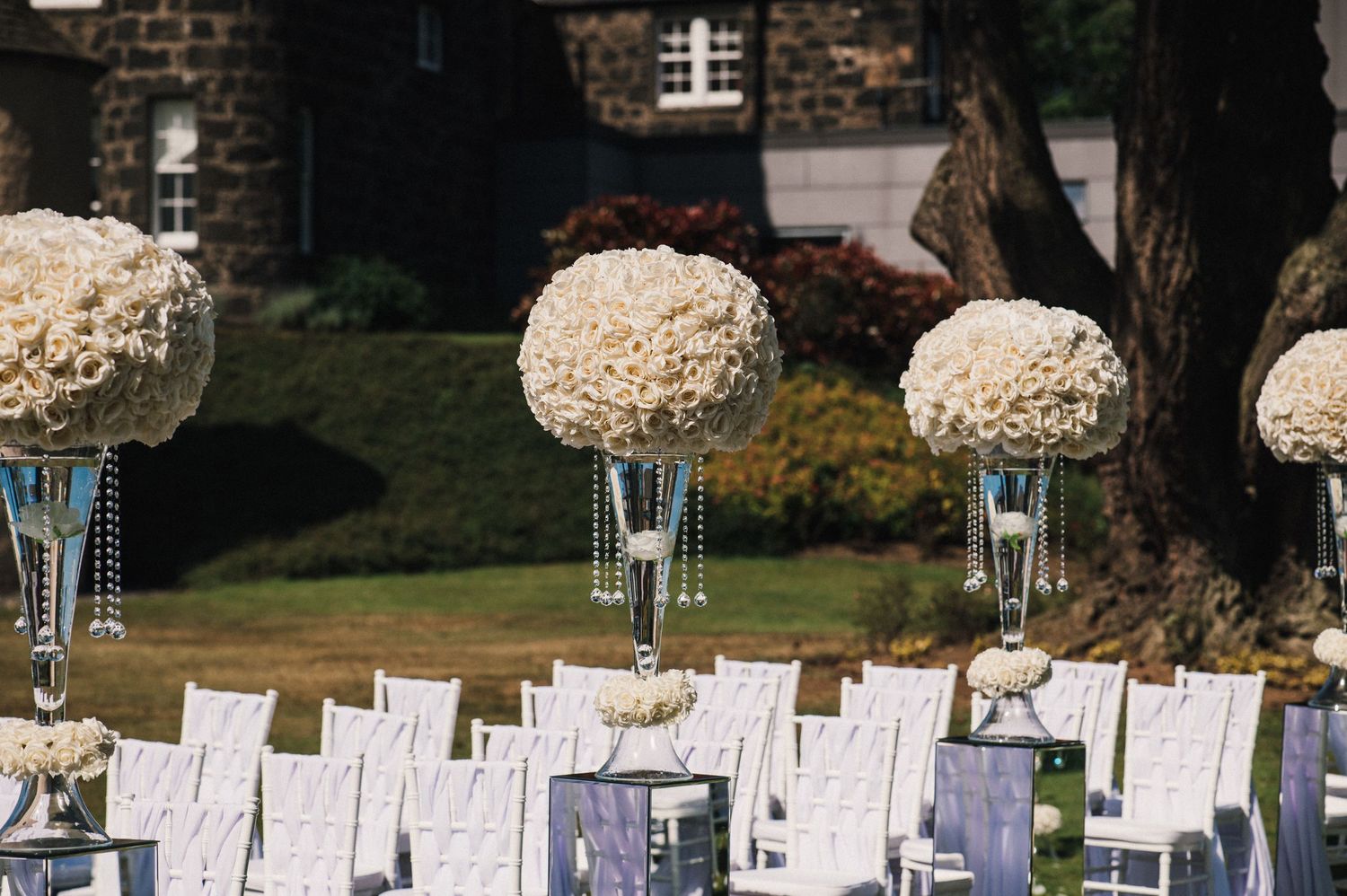 Elegant white hydrangea centerpieces in tall glass vases decorate wedding reception tables.