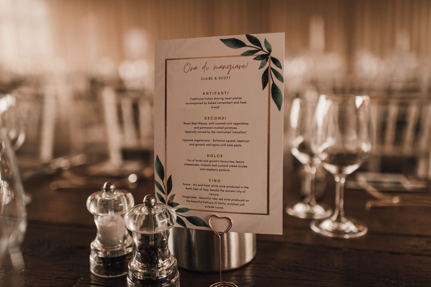 Wedding menu card displayed on elegant table setting with wine glasses and table decor.