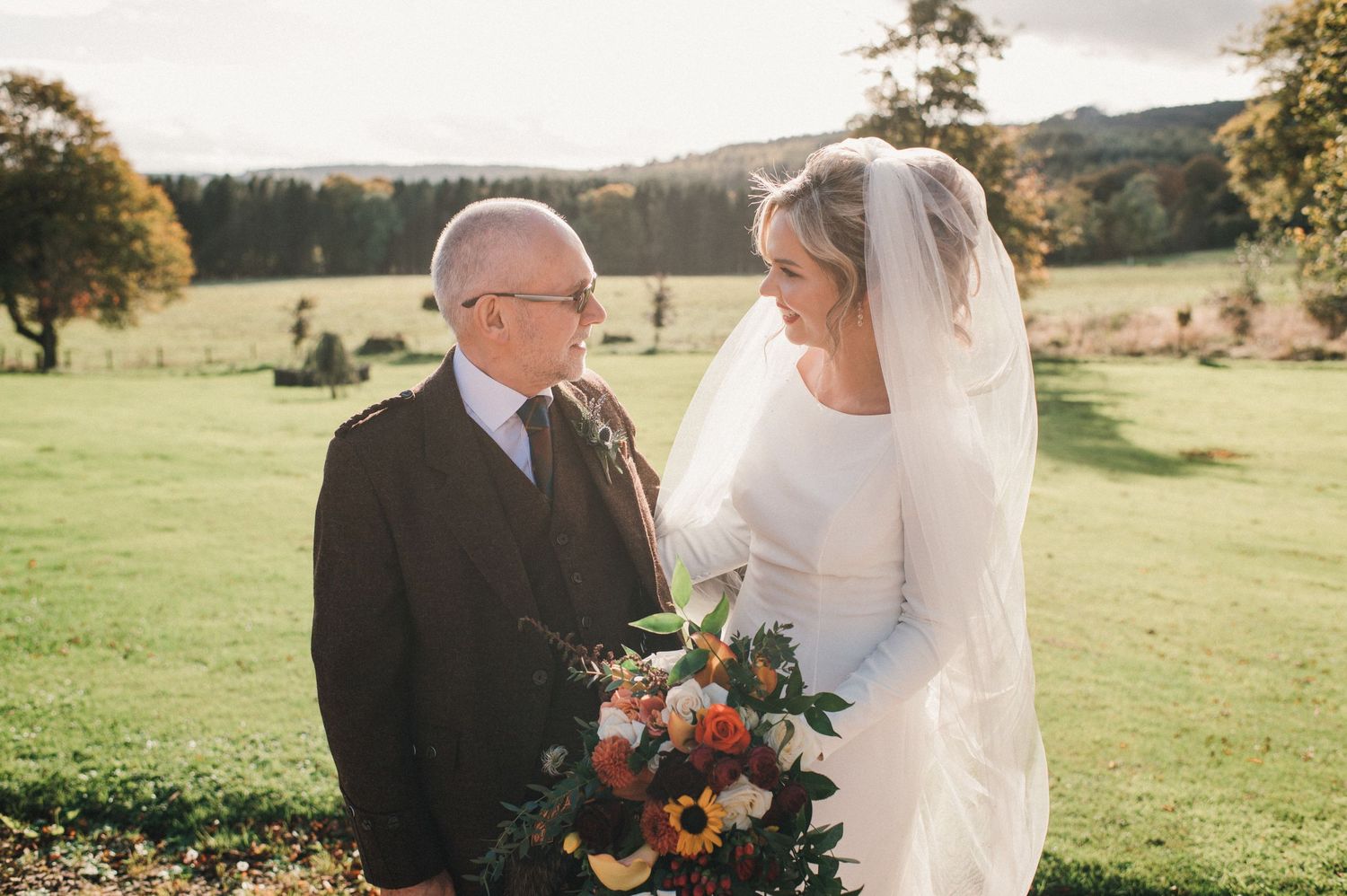 Outdoor wedding portrait capturing a tender moment against rolling hills and autumn scenery.