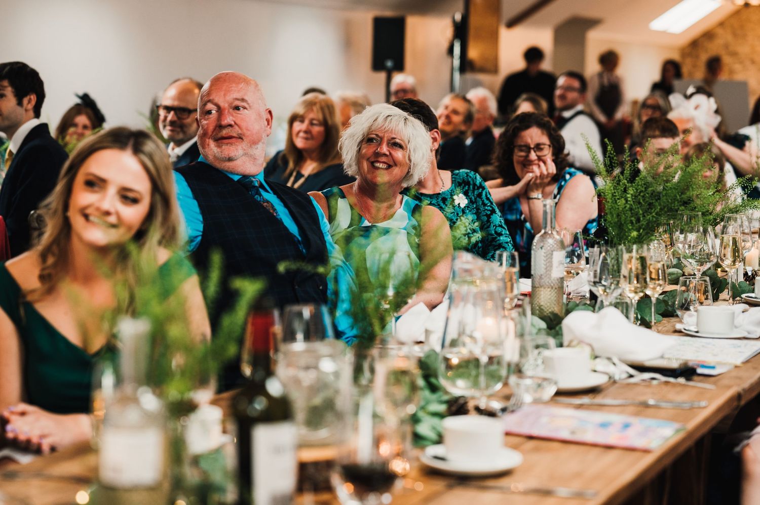 Wedding guests smile and enjoy themselves at an elegantly decorated reception dinner.
