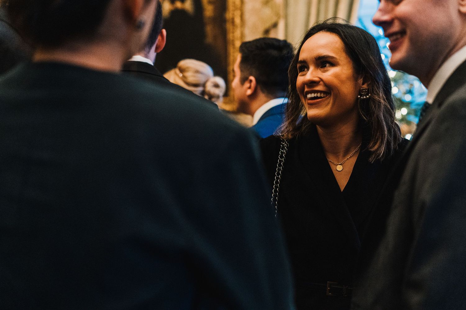 Guests share animated conversation during an elegant indoor evening event.