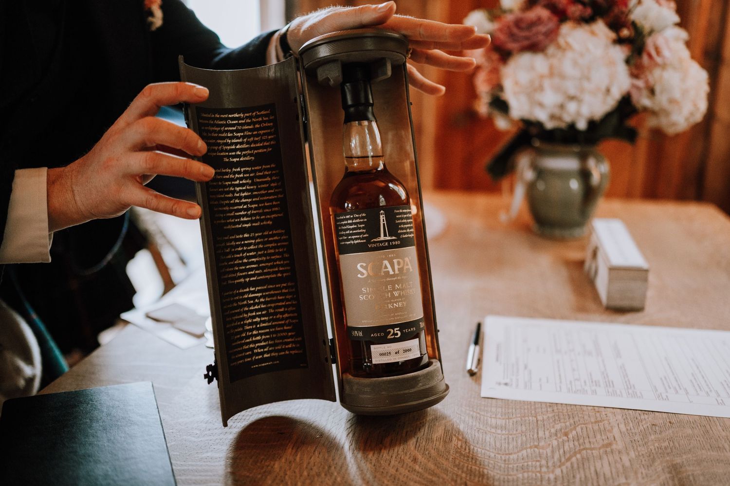 A bottle of whiskey being presented in a wooden case with text on the interior.