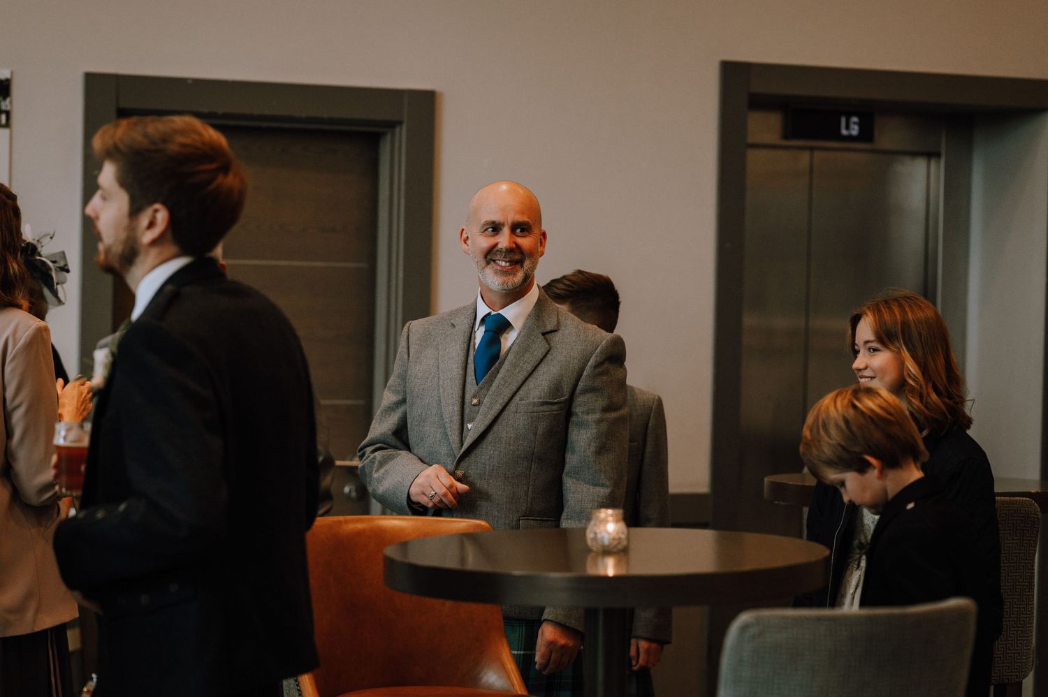 Group of people gathered in a modern office lobby around tables during an event.