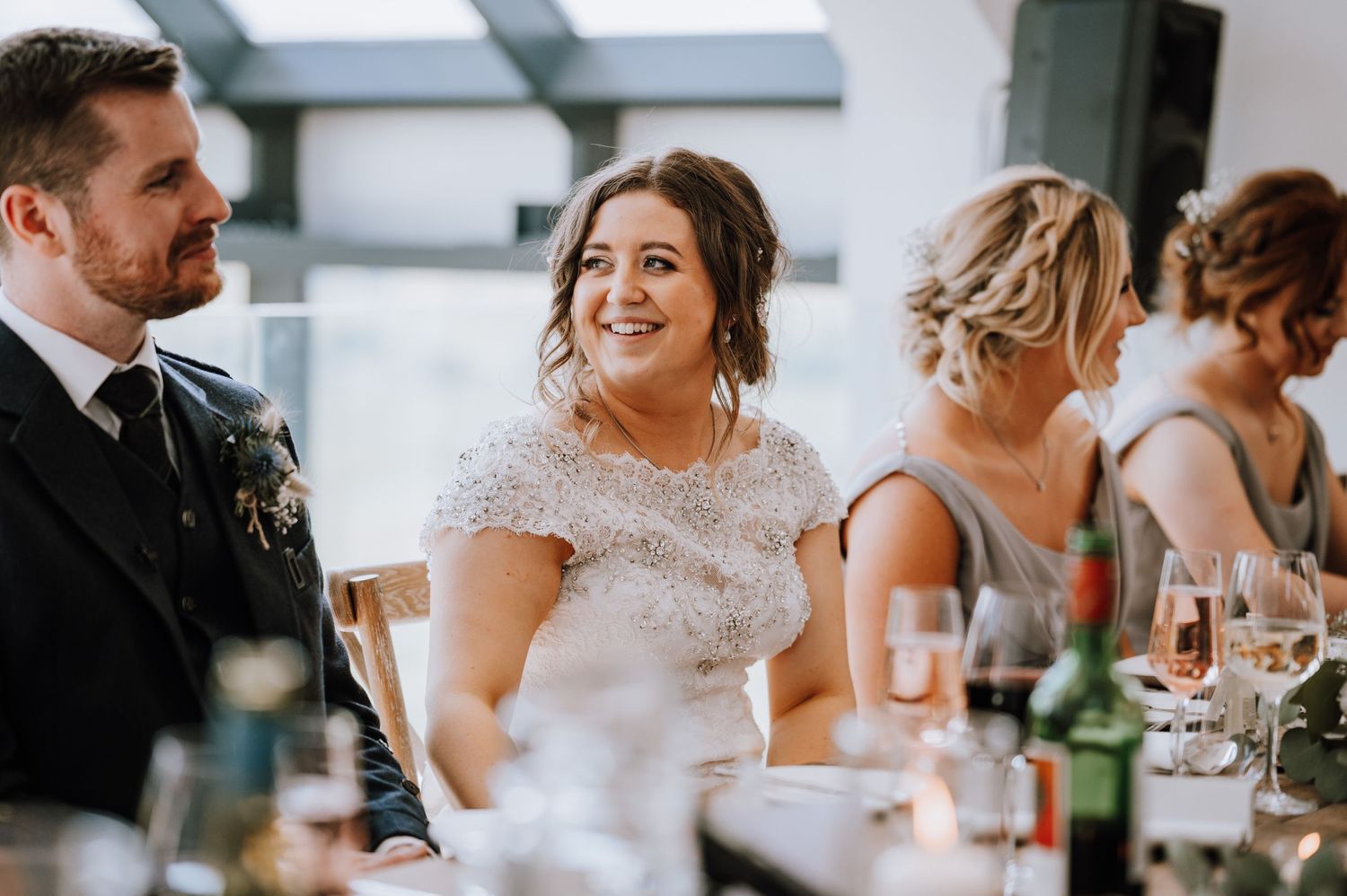 Wedding party members enjoying conversation at reception dinner table.