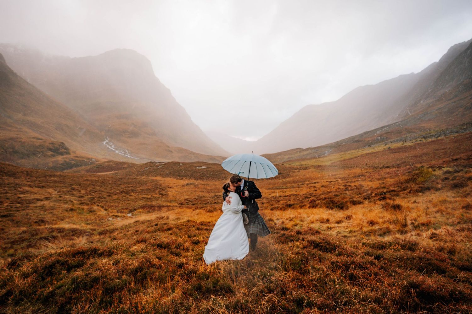 Misty Scottish highlands create romantic backdrop for wedding photography.