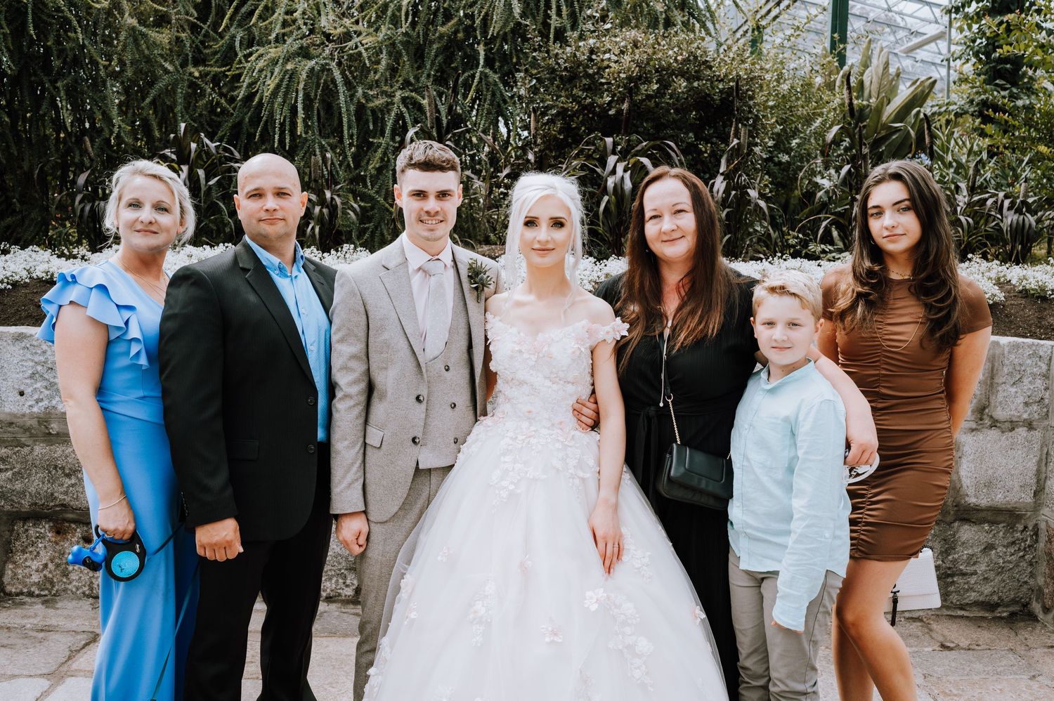 A wedding group photo with family members in coordinated formal attire.