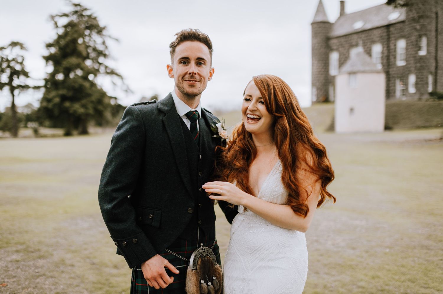 A bride and groom share a laugh together during their Scottish castle wedding photoshoot.