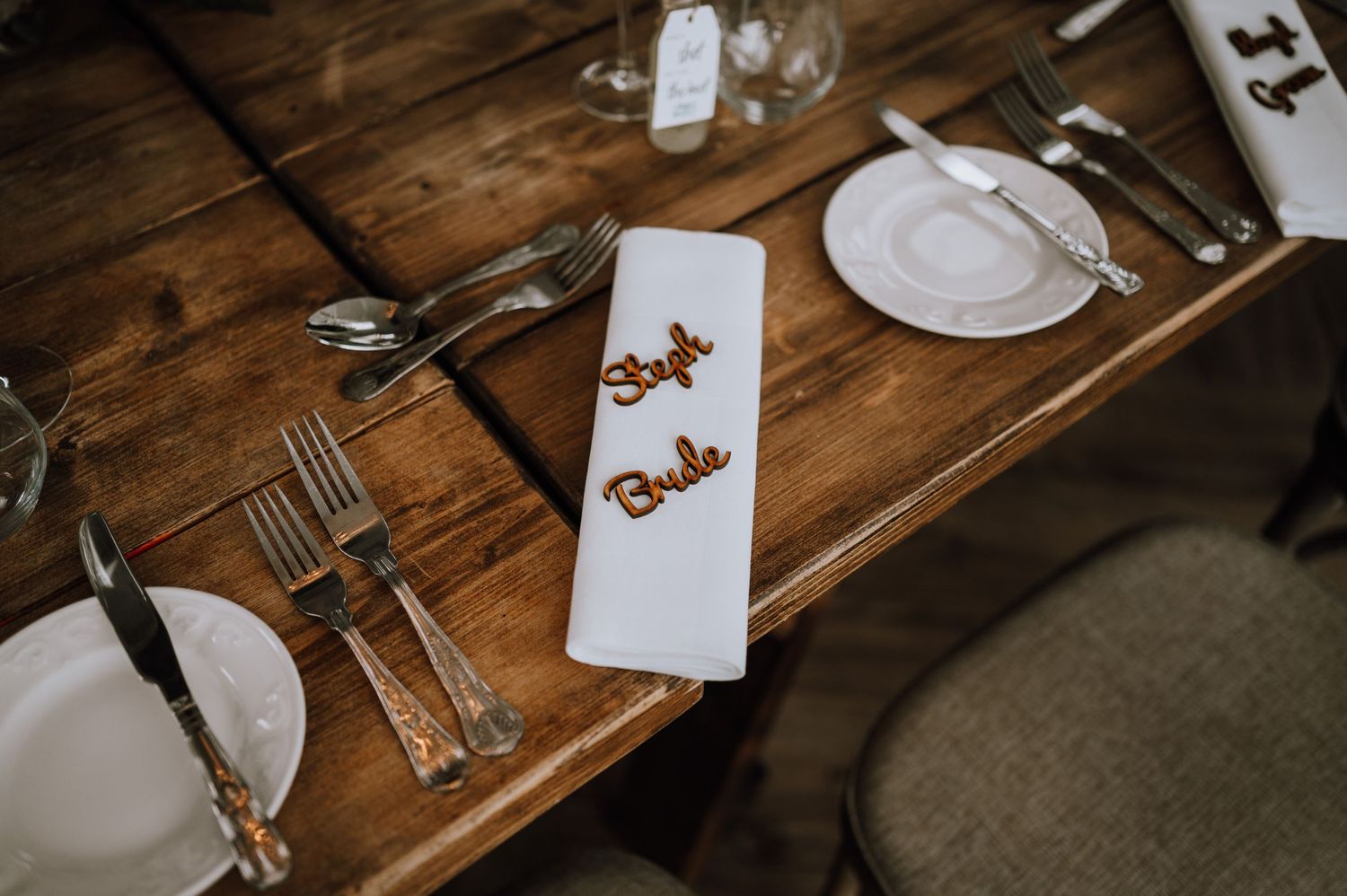 Close-up of wedding place setting on rustic wooden table with elegant name cards.