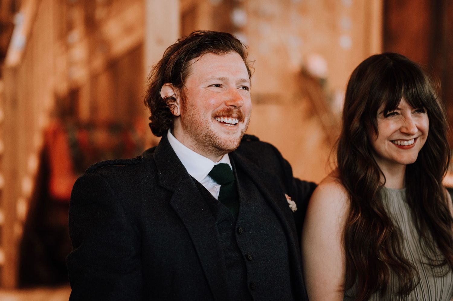 A couple shares a joyful moment at their wedding in a warmly lit wooden interior.