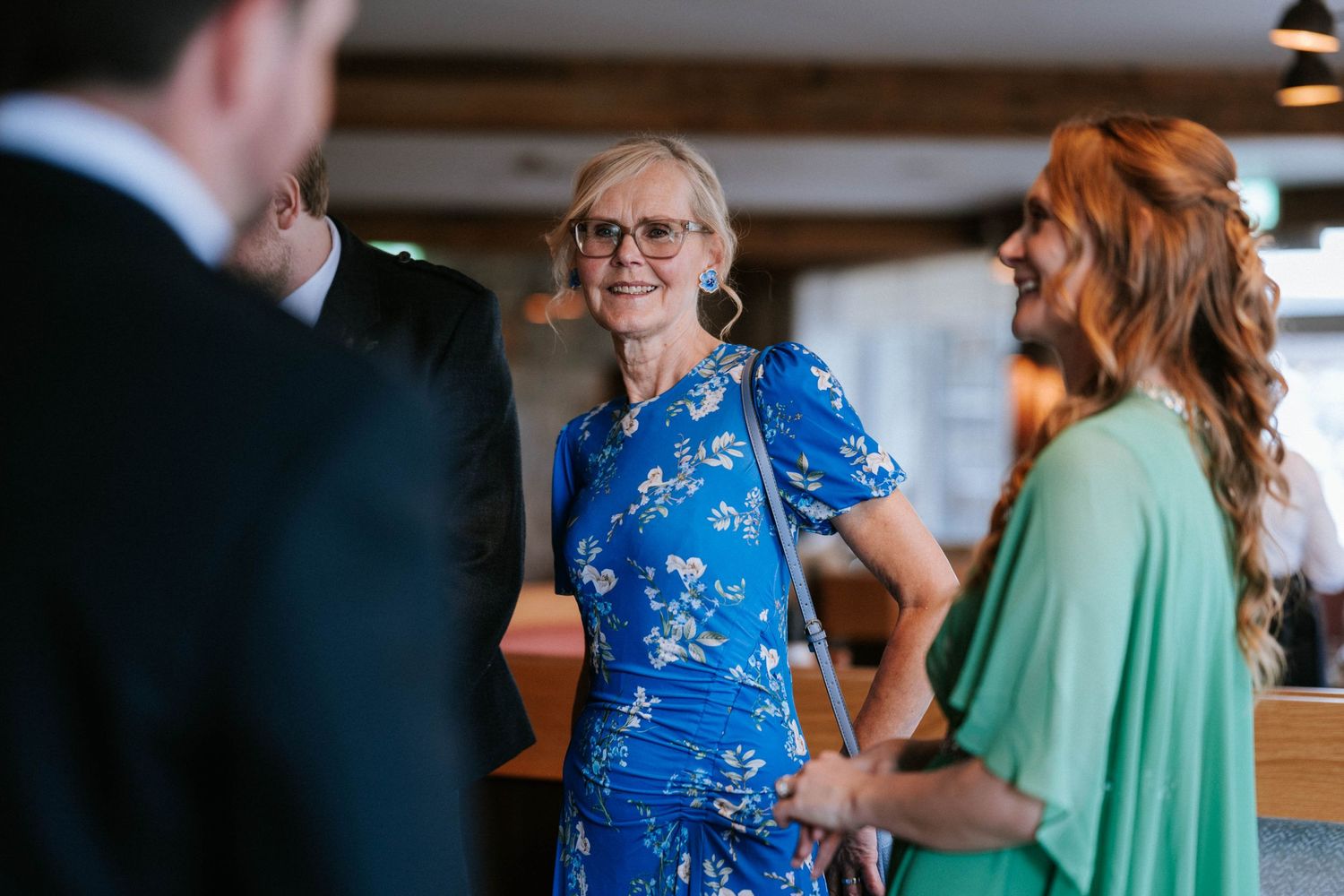 Wedding guests chatting during a reception in a rustic indoor venue.