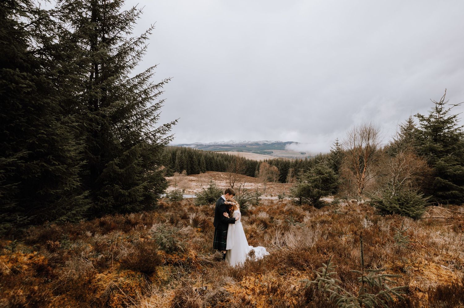 Scenic wedding photography in Scottish Highlands with misty mountains and rustic wilderness backdrop.
