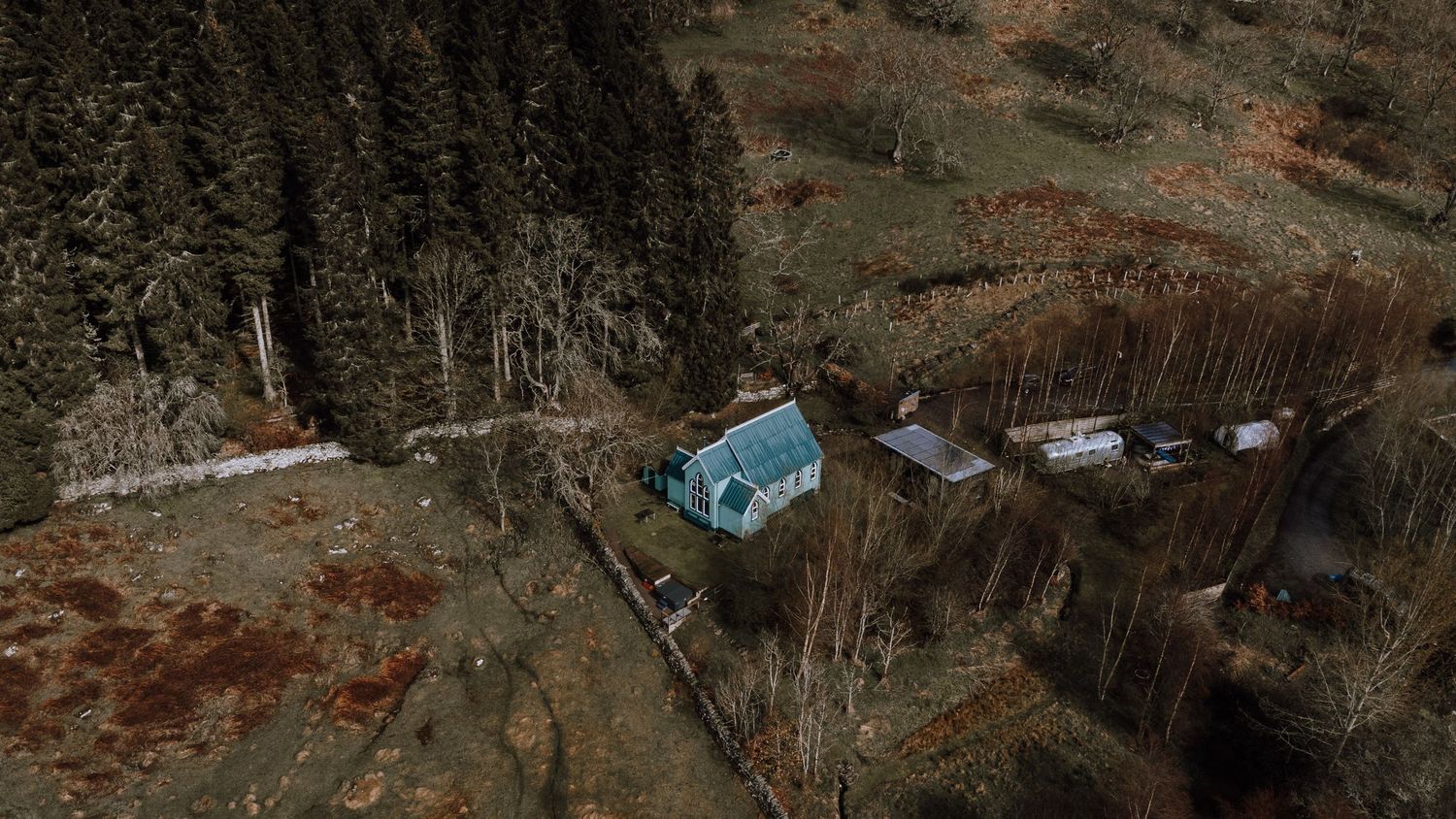 Aerial view of a blue cabin nestled in a remote mountainous landscape.