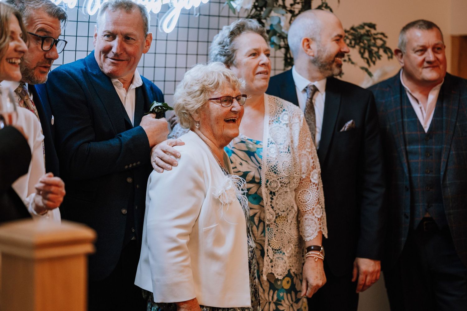 Group of guests gathered together at an indoor wedding celebration.