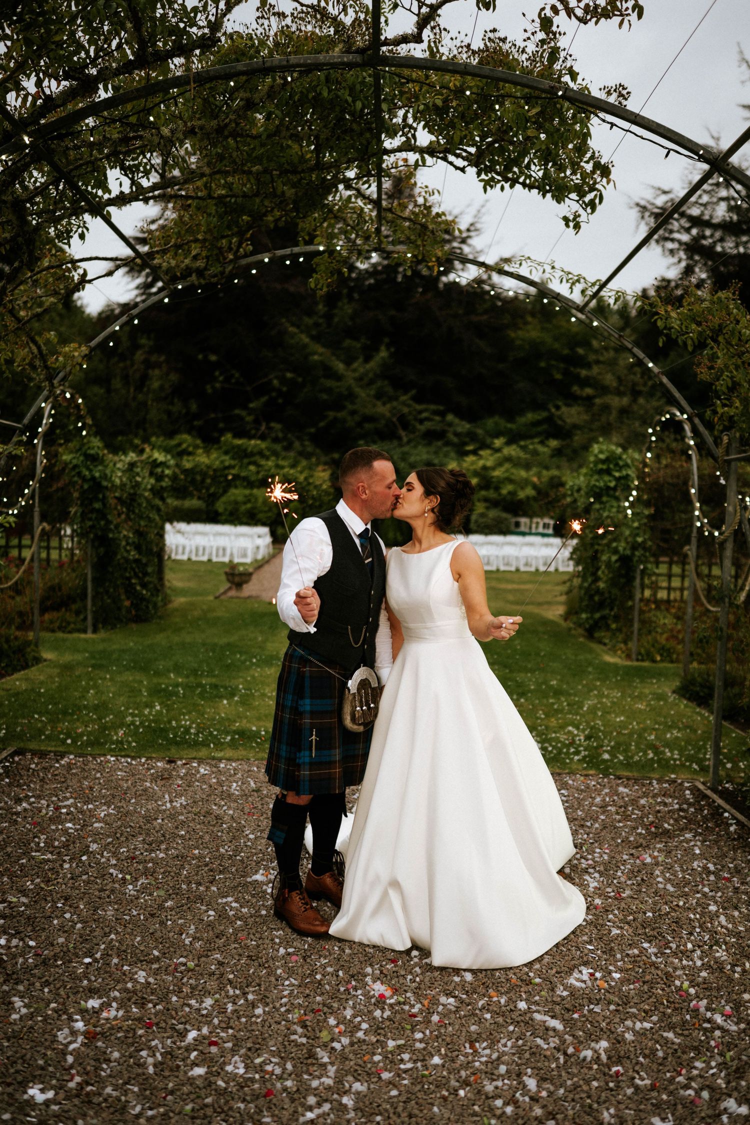 Couple celebrating their wedding day outdoors with confetti in a garden setting.